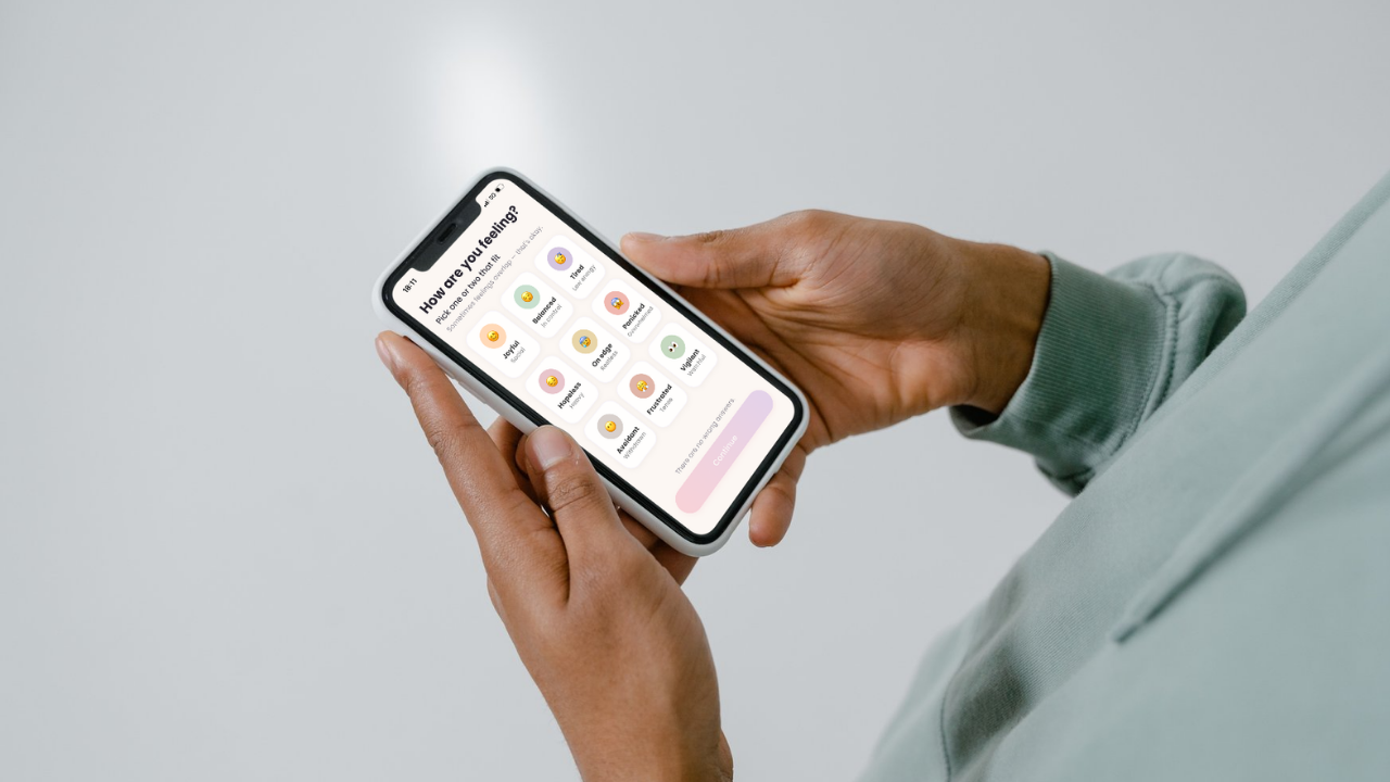 Hand holding a phone showing the Unwind Minds app
